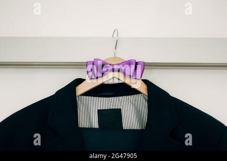 Jacket with striped lining and purple bow tie on a hanger. Stock Photo