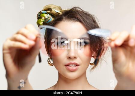 Female in headscarf is looking at the camera through glasses. Stock Photo