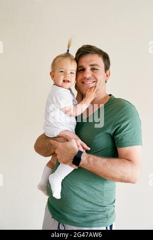 Smiling dad holds a smiling baby in his arms. Portrait Stock Photo