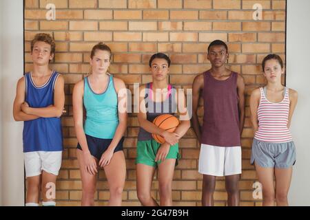 High school kids leaning against the wall in basketball court Stock Photo