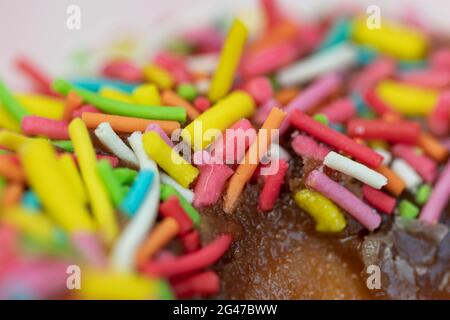Pastries concept. Donuts with chocolate glaze with colorfull sprinkles, on a pink plate. Macro. Stock Photo
