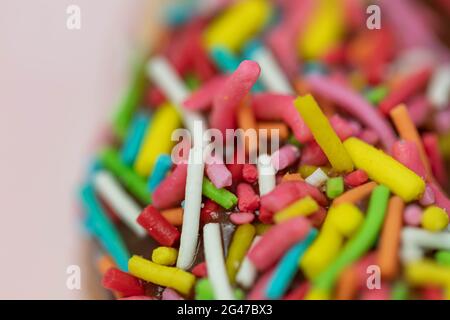 Pastries concept. Donuts with chocolate glaze with colorfull sprinkles, on a pink plate. Macro. Stock Photo