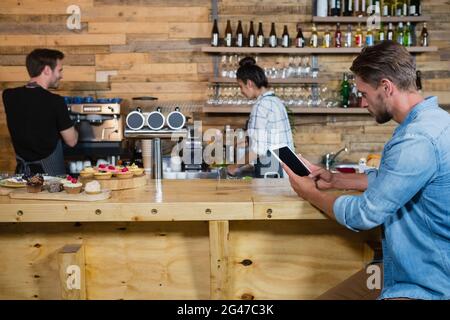 Man using digital tablet at counter Stock Photo