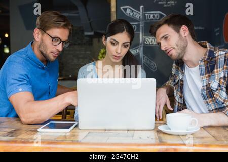 Friends using laptop while having coffee Stock Photo