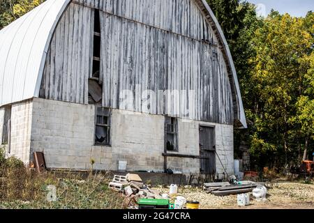 Closeup of an old white barn with various junk in the foreground. Stock Photo