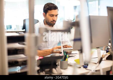 Businessman using mobile phone at desk in office Stock Photo