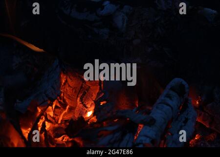 Smoldered logs burned in vivid fire close up. Atmospheric background with flame. Stock Photo