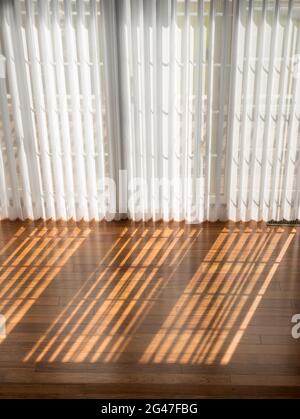 Vertical blinds cast shadows on a newly installed Brazilian Cherry hardwood floor Stock Photo