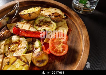set of baked vegetables zucchini tomato potatoes bell pepper on wooden plate Stock Photo