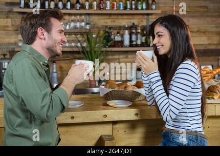 Couple interacting each other while having coffee at counter Stock Photo
