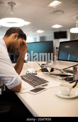 Tensed businessman sitting in office Stock Photo
