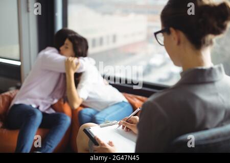 Couple embracing each other in front of marriage counselor Stock Photo
