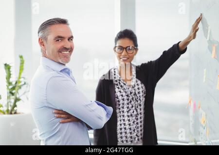 Portrait of smiling colleagues discussing over sticky note Stock Photo