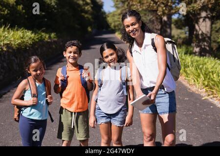 Portrait of happy teacher and students with tablet PC on street Stock Photo