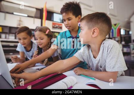Attentive schoolkid using laptop in library Stock Photo
