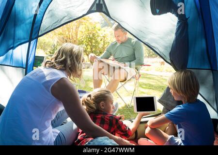 Kids and mother using tablet while father looking at the map Stock Photo