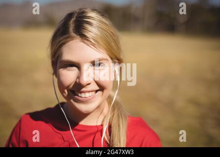 Portrait of fit woman listening music on headphones during obstacle course Stock Photo