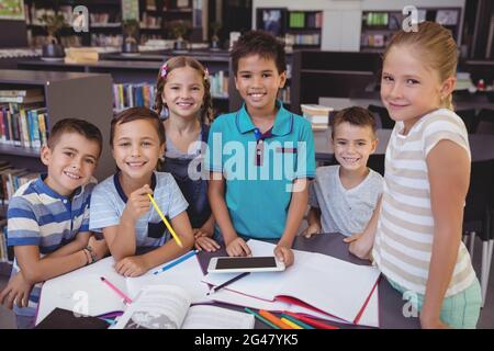 Portrait of smiling schoolkid using digital tablet in library Stock Photo