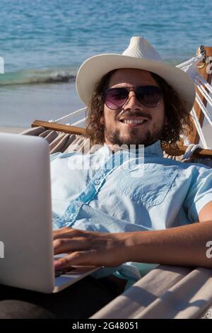 Man using laptop while relaxing on hammock Stock Photo