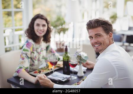 Portrait of romantic couple holding hands while having meal Stock Photo