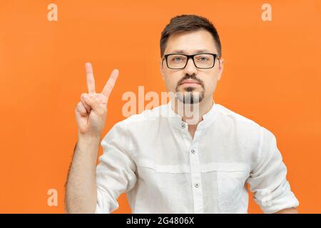 Young handsome man wearing in white shirt over isolated yellow background showing and pointing up with fingers number two. Male showing victory sign.  Stock Photo