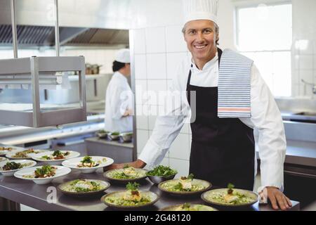 Portrait of happy chef with appetizer plates at order station Stock Photo