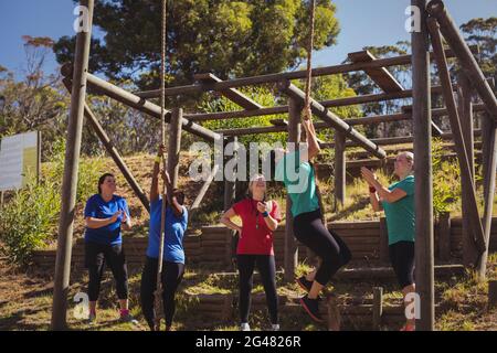 Female trainer instructing women to climb a rope in the boot camp Stock Photo
