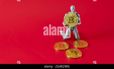 Bitcoin Cryptocurrency. Digital Currency of The Future. Selective focus of a doll on the knee holding bitcoin replica. Stock Photo