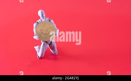Bitcoin Cryptocurrency. Digital Currency of The Future. Selective focus of a doll on the knee holding bitcoin replica. Stock Photo