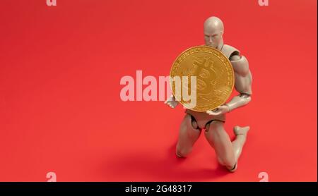 Bitcoin Cryptocurrency. Digital Currency of The Future. Selective focus of a doll on the knee holding bitcoin replica. Stock Photo