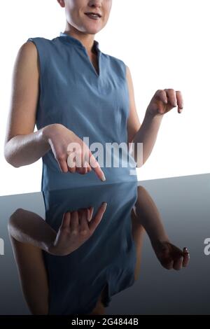 Mid section of smiling businesswoman using imaginary interface at table Stock Photo