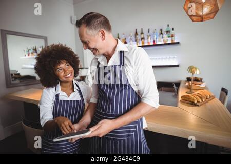 Waiter and waitress using digital tablet at counter Stock Photo
