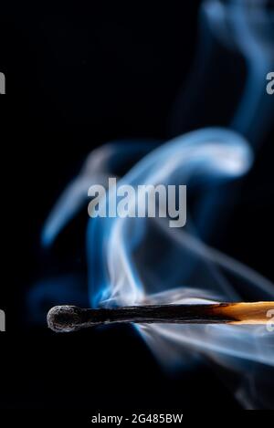 Close-up shot of an extinguished match with smoke on a black background. Copy space. Stock Photo