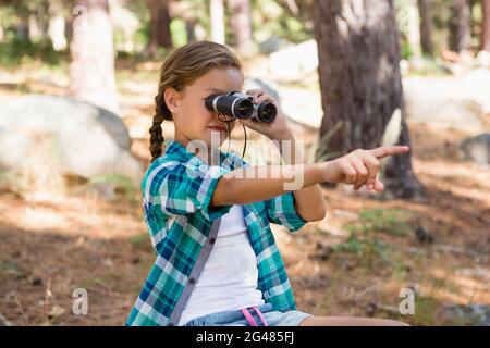 Girl looking through binoculars in the forest Stock Photo