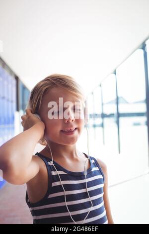 Elementary girl with eyes closed listening music through headphones Stock Photo