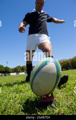 Player kicking rugby ball on grassy field Stock Photo