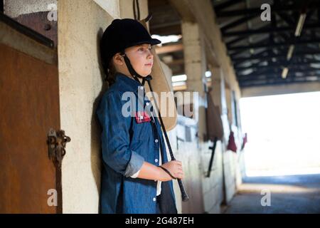 Girl leaning on wall in the stable Stock Photo