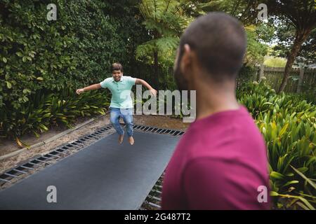 Father looking at son jumping on trampoline Stock Photo