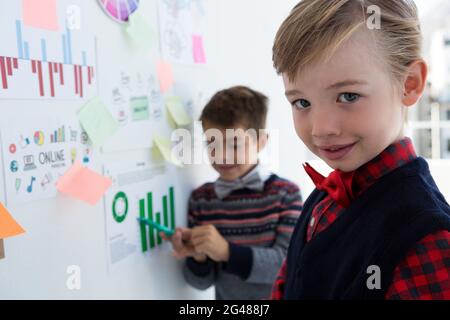 Kids as business executives discussing over whiteboard Stock Photo