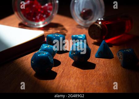 Close-up image of blue marbled role-playing gaming dice on a red wooden surface in the sunlight. Stock Photo