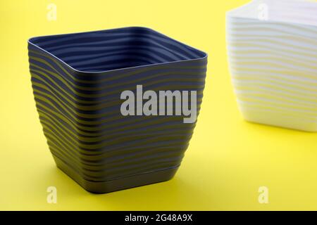 Empty plastic flower pot on a yellow background. Square flower container. Plastic containers for indoor plants. Stock Photo