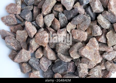 Red quartzite crumb on a white background top view. Decorative stone chips for landscaping. Crushed stone close-up. Stock Photo