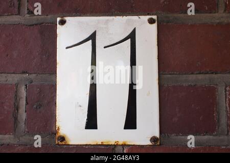 House number '11' attached to a brick wall Stock Photo