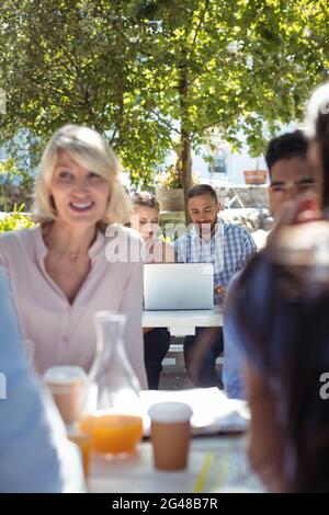 Friends interacting with each other and using laptop Stock Photo