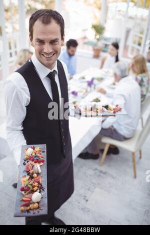 Portrait of smiling waiter holding food tray Stock Photo