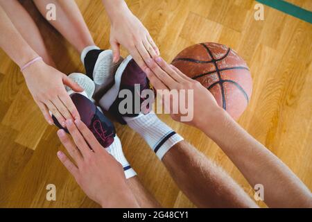 Friends exercising while sitting on hardwood floor in court Stock Photo