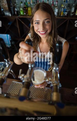 Portrait of beautiful barmaid pouring beer from tap in glass Stock Photo