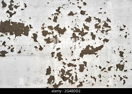 White paint peels off of an external wall revealing the plaster underneath. Stock Photo