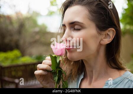 Close-up of beautiful woman with eyes closed smelling pink rose Stock Photo