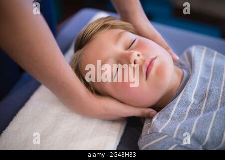 High angle view of boy with eyes closed receiving neck massage from female therapist Stock Photo